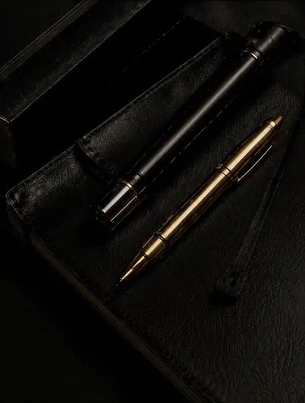 Mesa escura com caderno preto de luxo e canetas premium douradas em composição sofisticada e minimalista